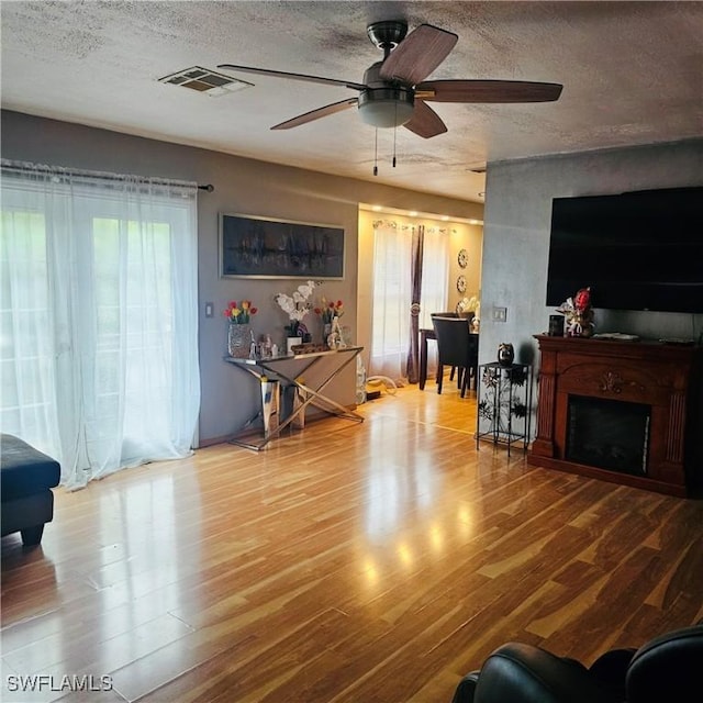 3411 22nd St SW, Lehigh Acres, FL 33976 - living area with a ceiling fan, a textured ceiling, wood finished floors, and a fireplace
