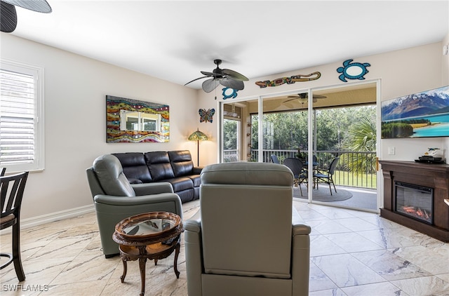 10530 Amiata Way Unit 201, Fort Myers, FL 33913 - living area with ceiling fan, a glass covered fireplace, light marble finish flooring, and baseboards