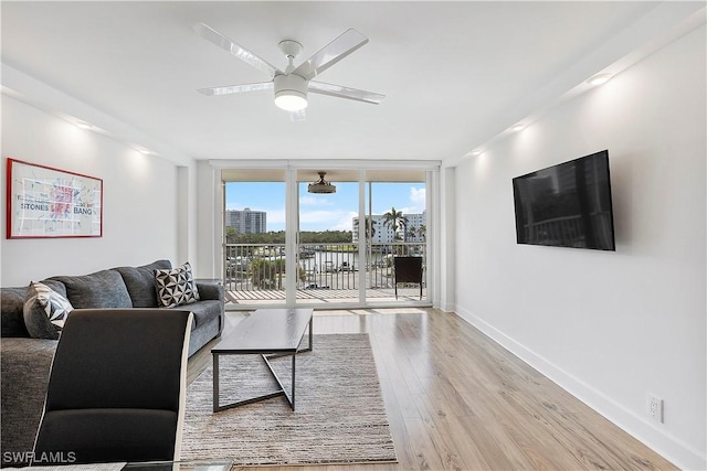 5 Bluebill Ave Unit 410, Naples, FL 34108 - living room featuring ceiling fan, light wood-style floors, and a wall of windows