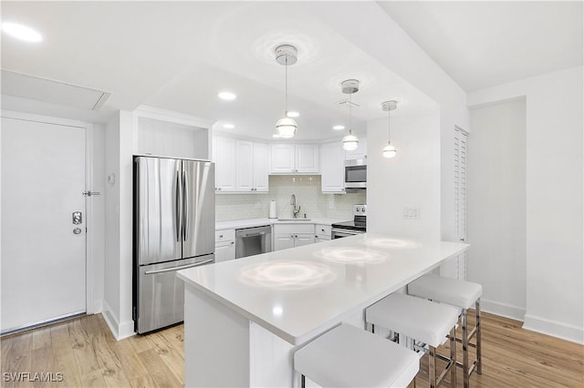 5 Bluebill Ave Unit 410, Naples, FL 34108 - kitchen with appliances with stainless steel finishes, a peninsula, a kitchen breakfast bar, light countertops, and white cabinets