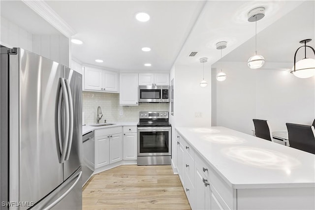5 Bluebill Ave Unit 410, Naples, FL 34108 - kitchen featuring stainless steel appliances, a peninsula, light countertops, white cabinets, and light wood finished floors