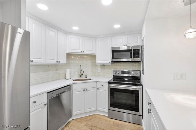 5 Bluebill Ave Unit 410, Naples, FL 34108 - kitchen featuring stainless steel appliances, white cabinets, light wood-style flooring, decorative backsplash, and recessed lighting