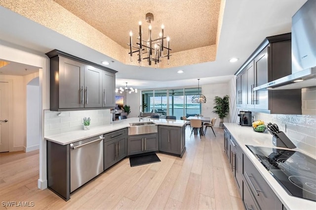 2104 W First St Unit 1402, Fort Myers, FL 33901 - kitchen featuring dishwasher, a chandelier, wall chimney exhaust hood, a tray ceiling, and light countertops