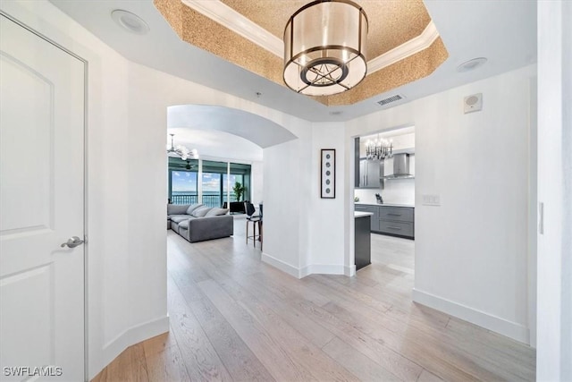 2104 W First St Unit 1402, Fort Myers, FL 33901 - hall with a chandelier, a tray ceiling, arched walkways, light wood finished floors, and crown molding