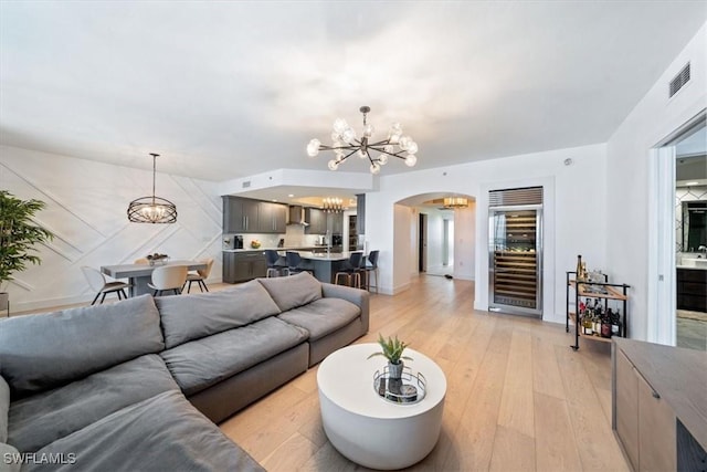 2104 W First St Unit 1402, Fort Myers, FL 33901 - living room featuring a chandelier, beverage cooler, arched walkways, light wood finished floors, and baseboards