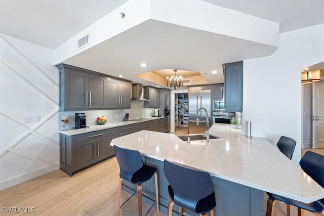 2104 W First St Unit 1402, Fort Myers, FL 33901 - kitchen with a sink, wall chimney range hood, a chandelier, light wood-type flooring, and a kitchen bar