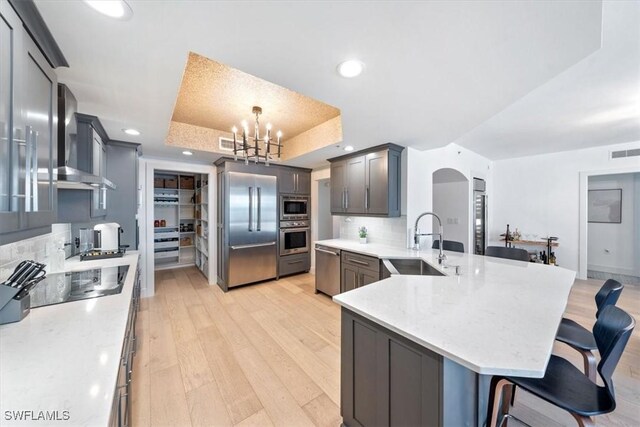 2104 W First St Unit 1402, Fort Myers, FL 33901 - kitchen with built in appliances, a sink, a peninsula, wall chimney exhaust hood, and light wood-type flooring