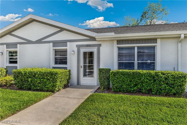 6843 Bogey Dr, Fort Myers, FL 33919 - doorway to property featuring stucco siding, a yard, and a shingled roof
