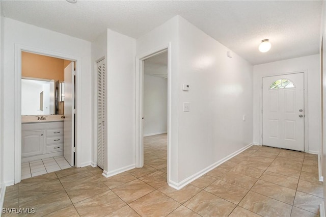 5737 Whitaker Rd Unit C203, Naples, FL 34112 - entryway featuring light tile patterned flooring, a textured ceiling, and baseboards