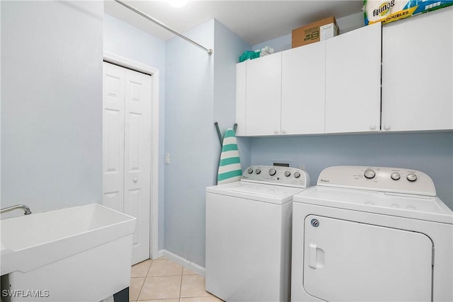 6810 Beach Resort Dr Unit 13, Naples, FL 34114 - washroom featuring washing machine and clothes dryer, cabinet space, light tile patterned floors, and baseboards