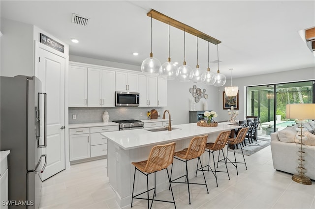 10415 Ventana Ln, Naples, FL 34120 - kitchen featuring appliances with stainless steel finishes, light countertops, a kitchen bar, tasteful backsplash, and white cabinets
