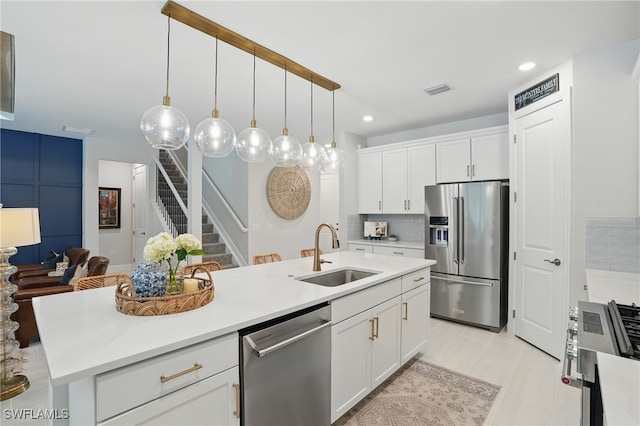 10415 Ventana Ln, Naples, FL 34120 - kitchen with appliances with stainless steel finishes, a kitchen island with sink, white cabinets, light countertops, and recessed lighting