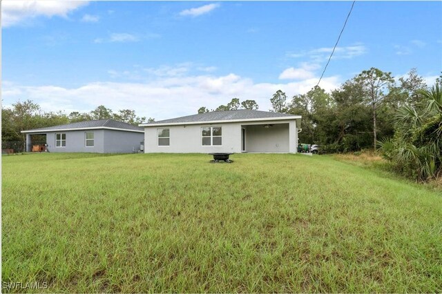 27130 Savoy Dr, Punta Gorda, FL 33955 - back of house featuring a lawn, stucco siding, and a fire pit