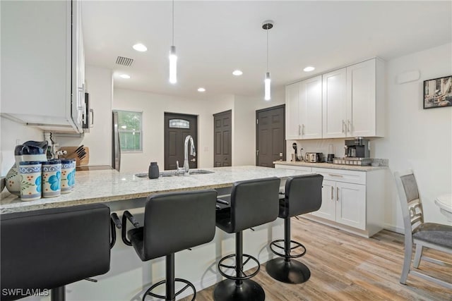 27130 Savoy Dr, Punta Gorda, FL 33955 - kitchen featuring a peninsula, white cabinetry, light stone countertops, a breakfast bar area, and recessed lighting