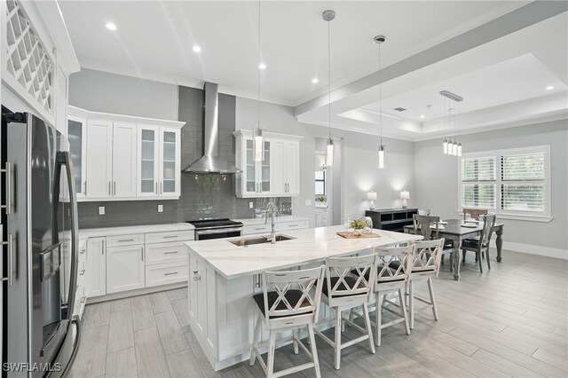 505 7th St NW, Naples, FL 34120 - kitchen with wall chimney exhaust hood, a sink, appliances with stainless steel finishes, tasteful backsplash, and white cabinetry