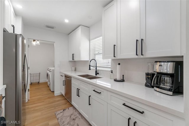 4126 Belair Ln Unit C6, Naples, FL 34103 - kitchen with stainless steel appliances, a sink, washer and clothes dryer, white cabinetry, and light wood-style floors