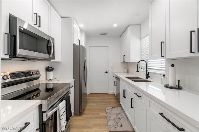 4126 Belair Ln Unit C6, Naples, FL 34103 - kitchen with appliances with stainless steel finishes, a sink, light wood-style flooring, white cabinetry, and recessed lighting