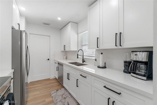 4126 Belair Ln Unit C6, Naples, FL 34103 - kitchen with a sink, stainless steel appliances, white cabinetry, light wood-style floors, and recessed lighting