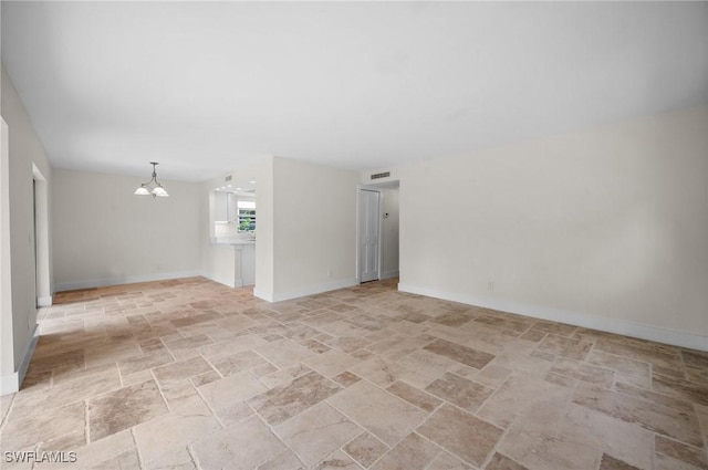 1549 Sandpiper St Unit 59, Naples, FL 34102 - empty room featuring a chandelier, light stone finish floors, and baseboards
