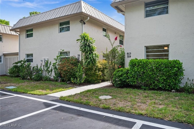 1549 Sandpiper St Unit 59, Naples, FL 34102 - view of home's exterior featuring stucco siding, a standing seam roof, metal roof, and uncovered parking