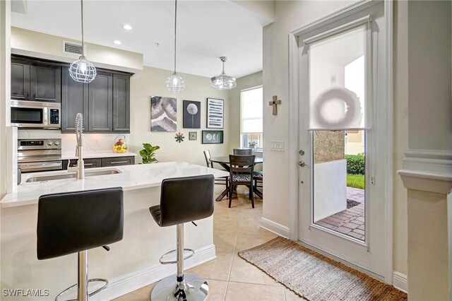 18273 Creekside Preserve Loop Unit 101, Fort Myers, FL 33908 - kitchen with stainless steel appliances, light stone countertops, a kitchen breakfast bar, hanging light fixtures, and recessed lighting