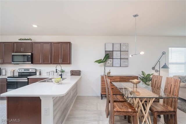 5213 Shell Mound Cir, Punta Gorda, FL 33982 - kitchen with stainless steel appliances, a sink, light countertops, dark brown cabinetry, and a peninsula