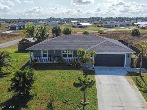 1220 Moore Run, Labelle, FL 33935 - view of front of property featuring a garage, concrete driveway, a front lawn, and a porch