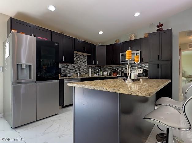 1220 Moore Run, Labelle, FL 33935 - kitchen with stainless steel appliances, light stone countertops, a kitchen bar, a kitchen island, and light marble finish flooring