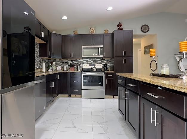 1220 Moore Run, Labelle, FL 33935 - kitchen with stainless steel appliances, lofted ceiling, light marble finish floors, light stone countertops, and decorative backsplash