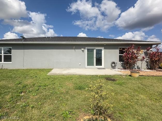 1220 Moore Run, Labelle, FL 33935 - back of house with a patio area, stucco siding, and a lawn