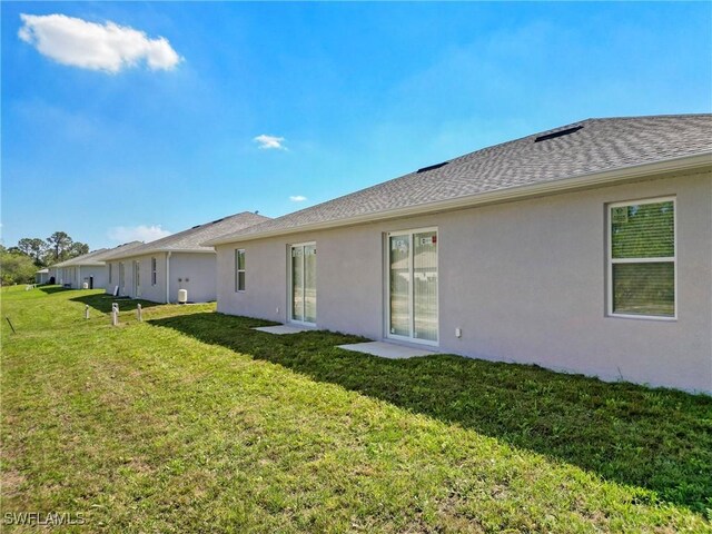 1404 W 12th St, Lehigh Acres, FL 33972 - back of property with a lawn, stucco siding, and roof with shingles
