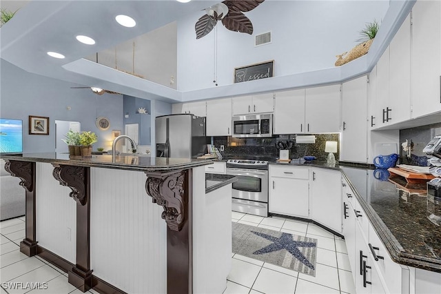 13460 Wild Cotton Ct, North Fort Myers, FL 33903 - kitchen featuring a towering ceiling, stainless steel appliances, a ceiling fan, light tile patterned floors, and decorative backsplash
