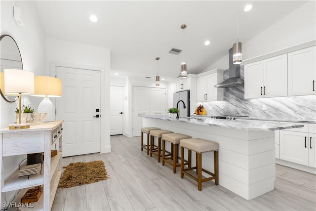 4014 Crayton Rd Unit B4, Naples, FL 34103 - kitchen featuring wall chimney range hood, tasteful backsplash, an island with sink, freestanding refrigerator, and white cabinets