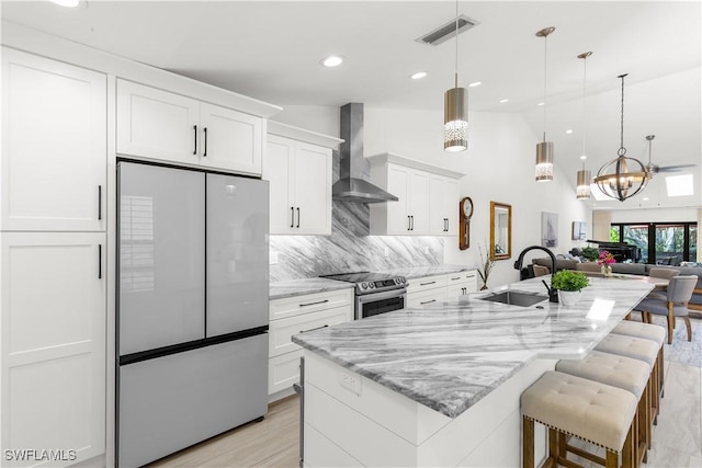 4014 Crayton Rd Unit B4, Naples, FL 34103 - kitchen featuring appliances with stainless steel finishes, wall chimney range hood, white cabinets, an island with sink, and a sink