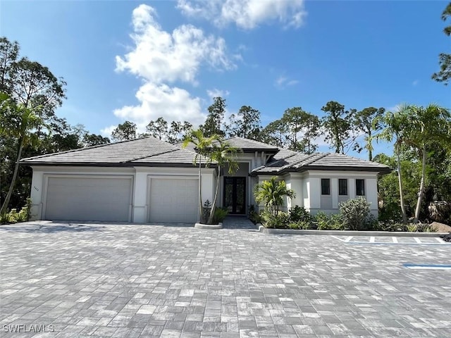 4472 Pine Ridge Rd, Naples, FL 34119 - prairie-style house with an attached garage, decorative driveway, french doors, and stucco siding