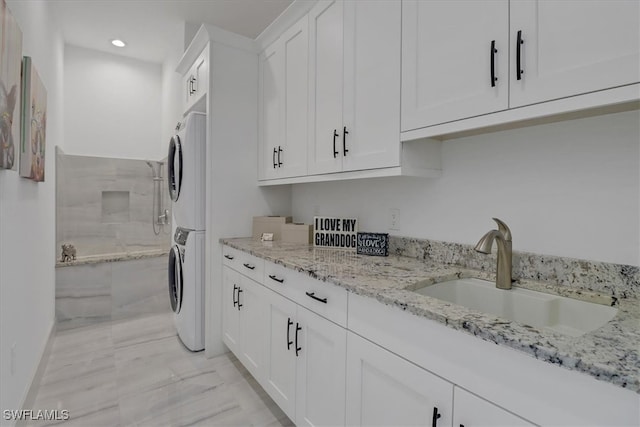 4472 Pine Ridge Rd, Naples, FL 34119 - laundry room featuring stacked washing machine and dryer, cabinet space, recessed lighting, and light marble finish floors