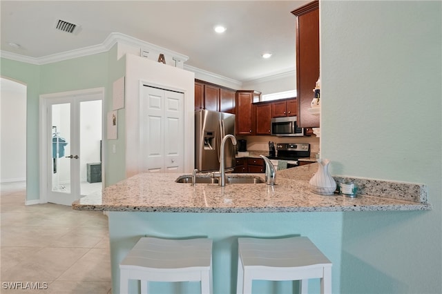 1886 Alameda Dr, Naples, FL 34120 - kitchen with appliances with stainless steel finishes, ornamental molding, a peninsula, light stone counters, and a kitchen breakfast bar