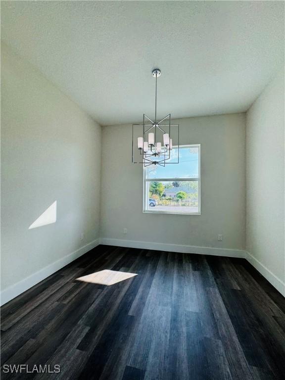 1062 Jay Ct, Labelle, FL 33935 - unfurnished room featuring dark wood-style flooring, baseboards, and a chandelier