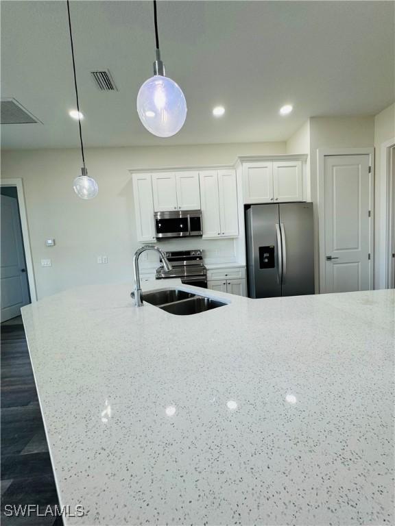 1062 Jay Ct, Labelle, FL 33935 - kitchen featuring stainless steel appliances, a sink, white cabinets, light stone counters, and recessed lighting