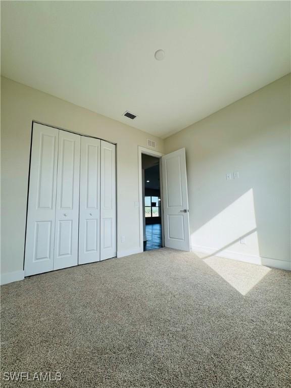 1062 Jay Ct, Labelle, FL 33935 - unfurnished bedroom featuring baseboards, a closet, and carpet flooring