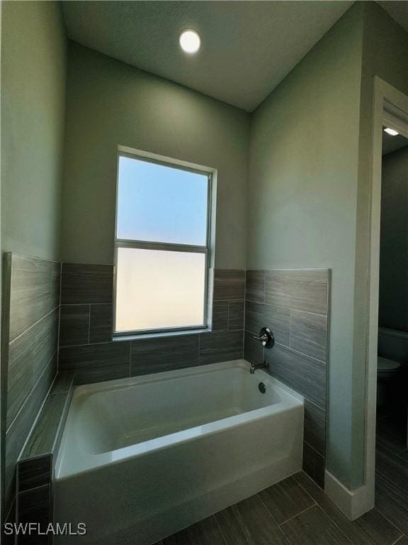 1062 Jay Ct, Labelle, FL 33935 - bathroom with a bath, toilet, wood finish floors, and baseboards