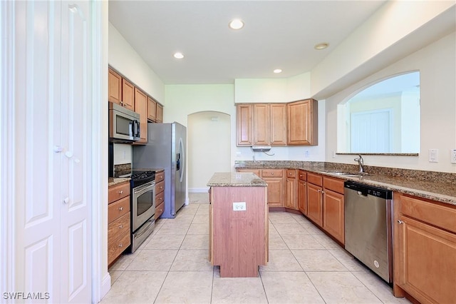1314 Corso Palermo Ct Unit 1802, Naples, FL 34105 - kitchen with stainless steel appliances, a sink, a center island, arched walkways, and light stone counters