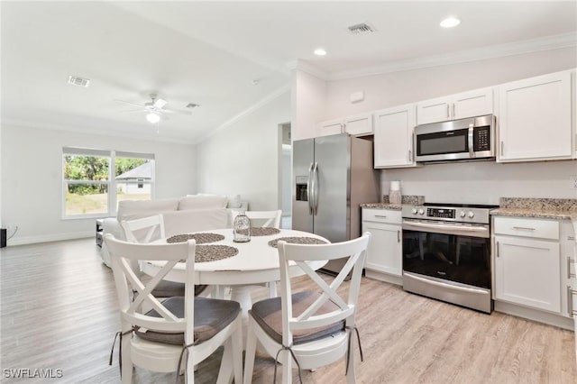 6009 S Moss Cir, Labelle, FL 33935 - kitchen featuring stainless steel appliances, vaulted ceiling, crown molding, light wood-style flooring, and white cabinetry