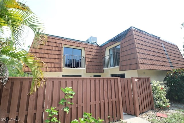 5216 Cedarbend Dr Unit 3, Fort Myers, FL 33919 - view of side of home with mansard roof, stucco siding, a balcony, a tiled roof, and a gate