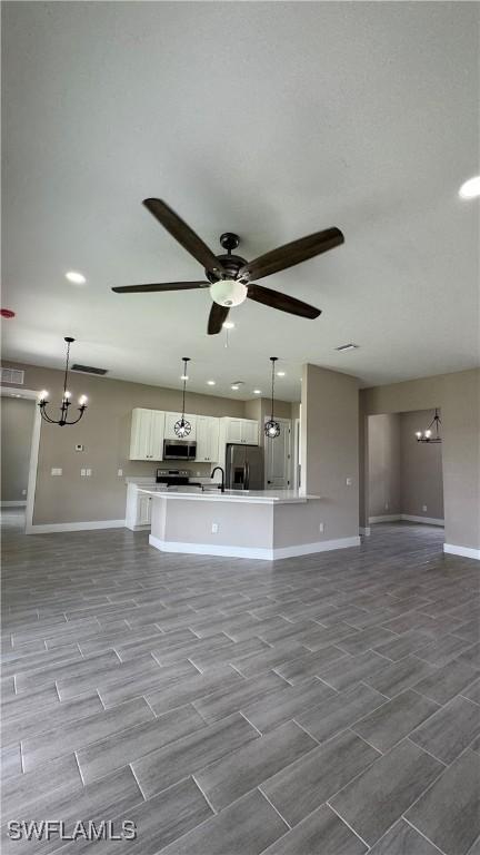 1115 Leader St, Labelle, FL 33935 - unfurnished living room featuring baseboards, ceiling fan, a chandelier, wood finished floors, and recessed lighting