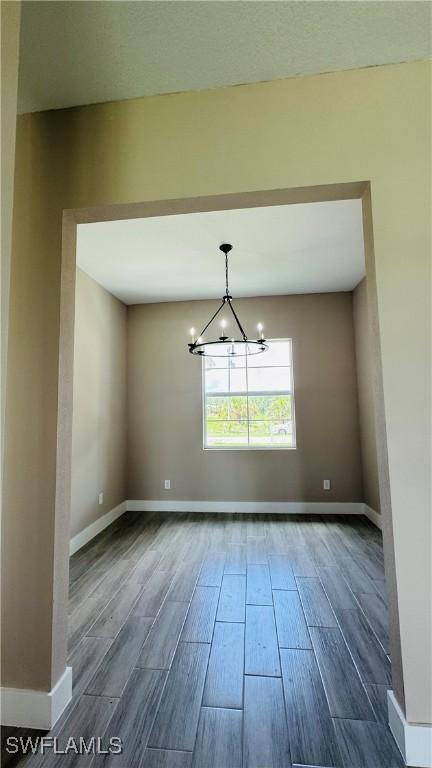 1115 Leader St, Labelle, FL 33935 - unfurnished room with wood finish floors, a chandelier, and baseboards
