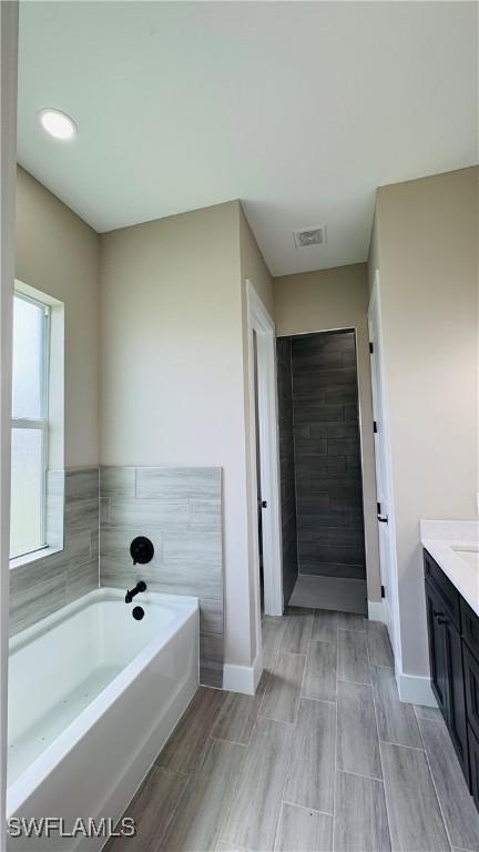 1115 Leader St, Labelle, FL 33935 - full bath with vanity, a bath, baseboards, and wood tiled floors