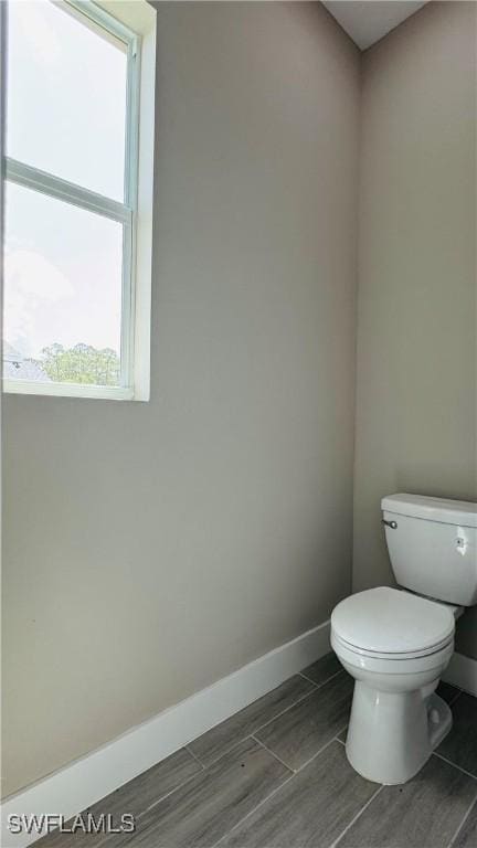 1115 Leader St, Labelle, FL 33935 - bathroom with baseboards, toilet, plenty of natural light, and wood finish floors