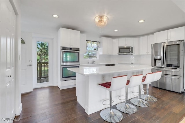 2940 14th Ave SE, Naples, FL 34117 - kitchen featuring stainless steel appliances, light countertops, dark wood-style flooring, a center island, and white cabinetry