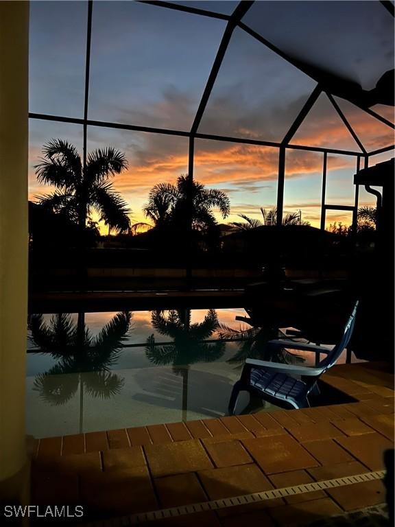1206 SW 18th Ave, Cape Coral, FL 33991 - patio terrace at dusk with glass enclosure, a patio area, and an outdoor pool